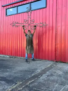 Raúl con el crucifijo frente al taller.