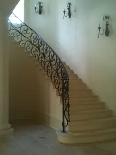 Escalera curva junto a pared clara.