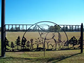 Panel con ciervos, árboles y montañas.