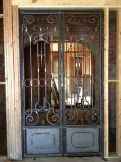 Puertas dobles con vidrio y volutas.