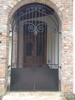 Puerta de reja en arco de ladrillo.