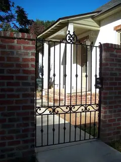 Puerta peatonal entre pilares de ladrillo.