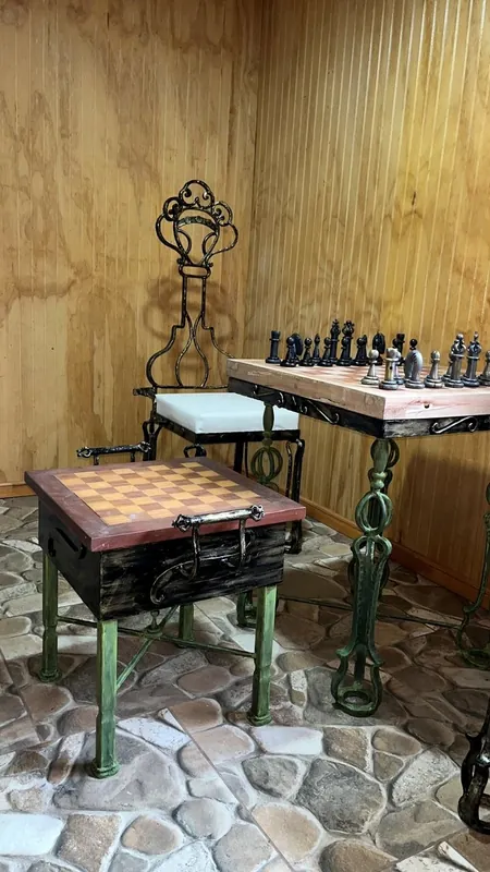 Mesa de ajedrez de hierro con piezas y sillas.