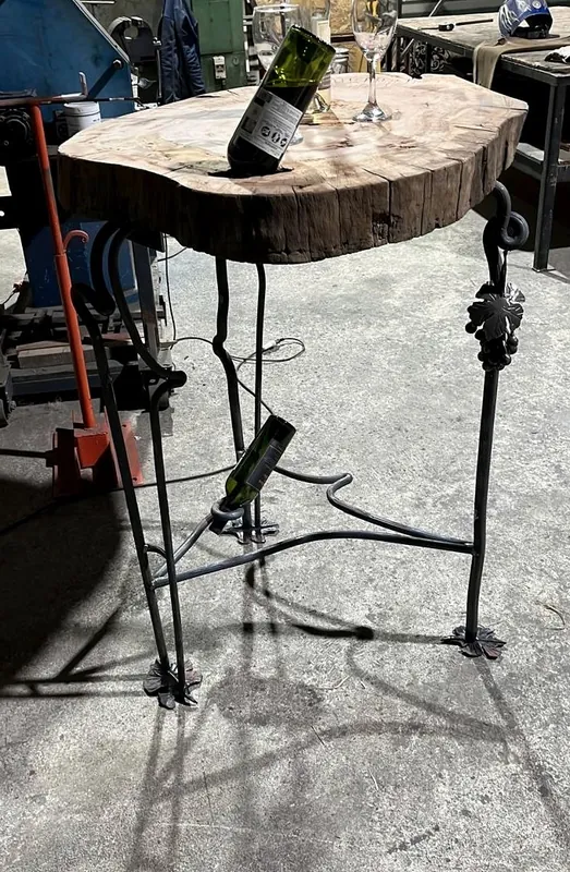 Mesa con una rodaja de madera y patas de hierro con forma de parra.